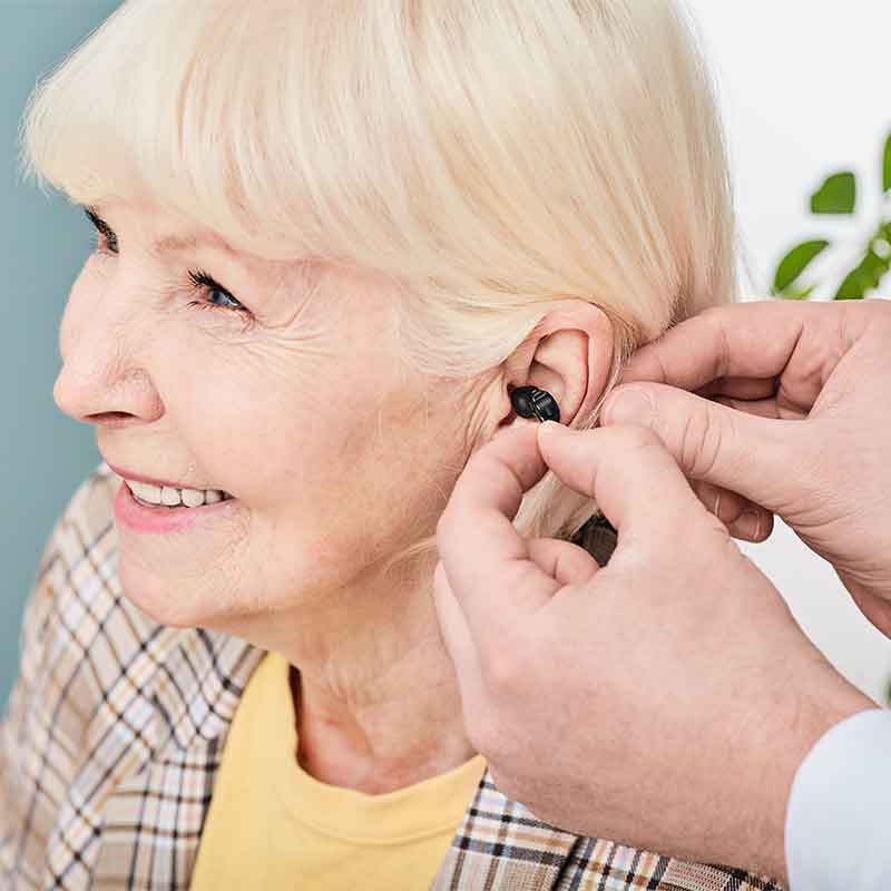 Woman being fitted with a discreet hearing aid. 