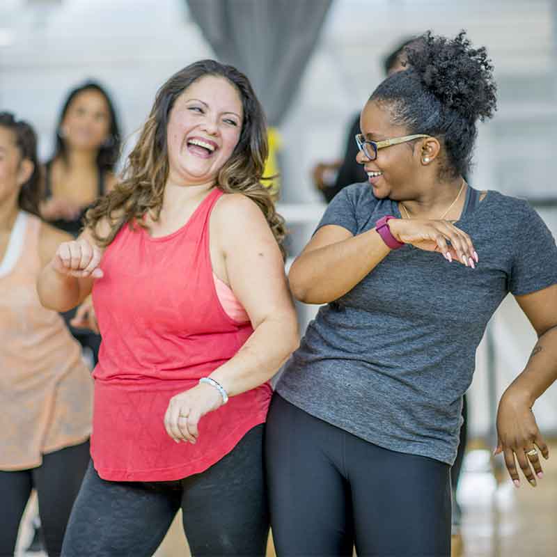 Two woman in an exercise class enjoying life with hearing aids. 
